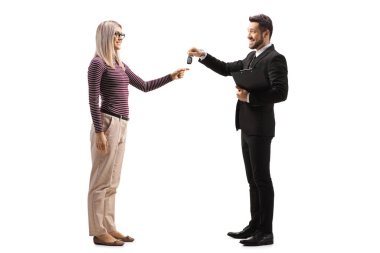 Satıcı, beyaz arka planda izole edilmiş genç sarışın bir kadına arabanın anahtarlarını veriyor.