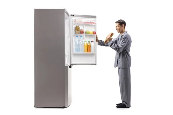 Человек Пижаме Ест Сэндвич Перед Холодильником Белом Фоне — стоковое фото
