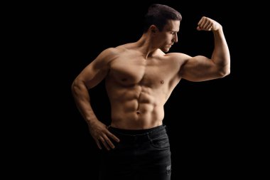Siyah arka planda kaslı, çıplak gövdeli, kaslı bir genç.