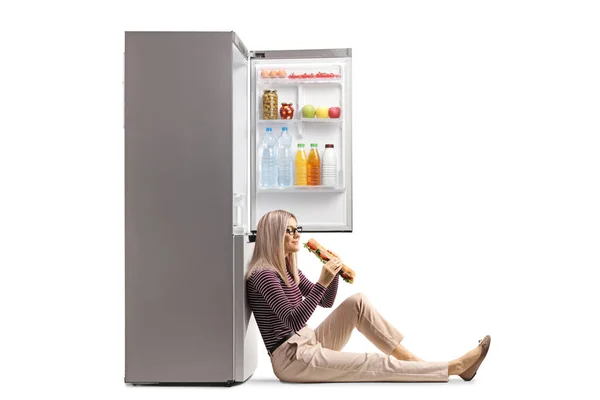 Женщина Сидящая Полу Опираясь Холодильник Поедая Сэндвич Белом Фоне — стоковое фото