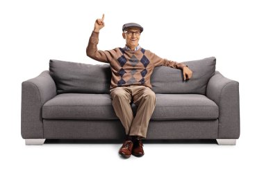 Kanepede oturan yaşlı bir adam beyaz arka planda izole edilmiş bir şekilde dikiliyor.