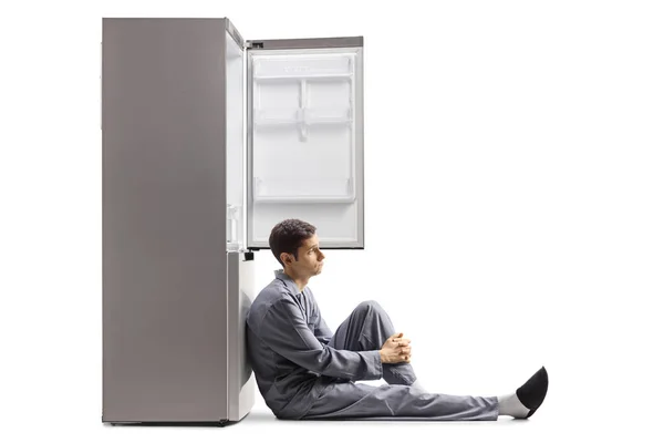 Smutný Muž Pyžamu Sedí Podlaze Opírá Prázdnou Ledničku Izolovanou Bílém — Stock fotografie