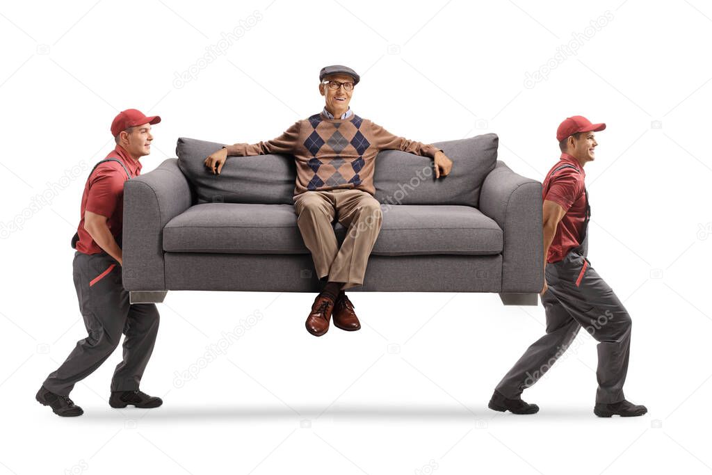 Movers carrying a sofa with an elderly man resting seated on the sofa isolated on white background
