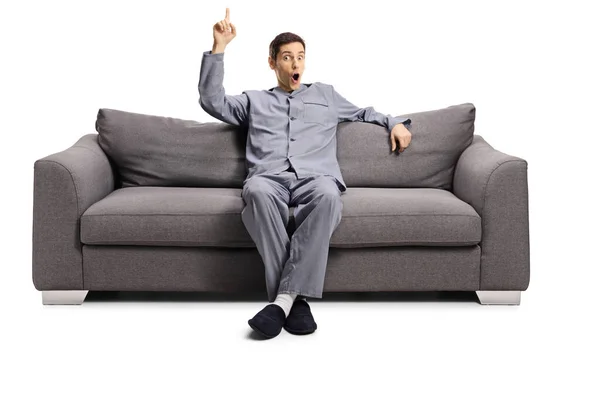 Ung Man Pyjamas Sittande Soffa Pekar Upp Isolerad Vit Bakgrund — Stockfoto