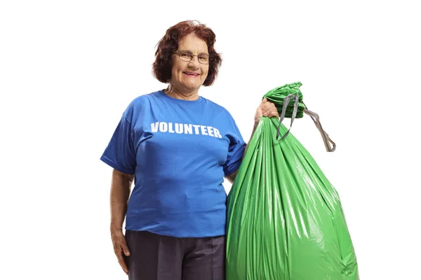 老年妇女自愿地拿着一个白色背景的绿色塑料袋 — 图库照片