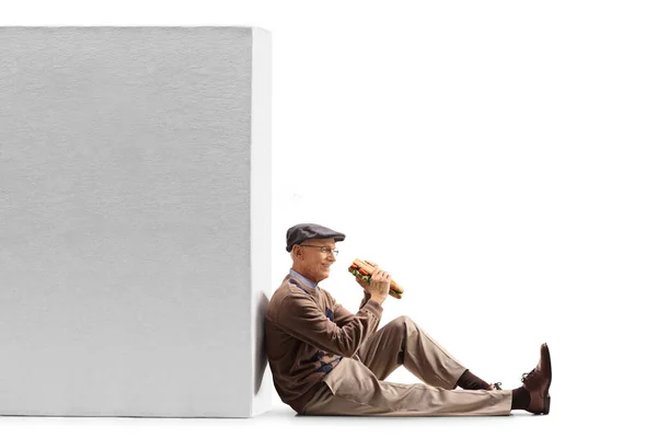Starší Muž Sendvič Sedí Podlaze Opírá Zeď Izolovanou Bílém Pozadí — Stock fotografie