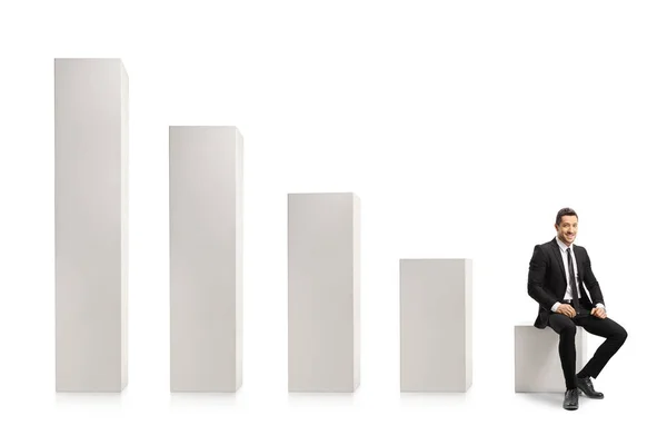 Businessman Sitting Shortest White Column Chart Smiling Camera Isolated White — Stock Photo, Image