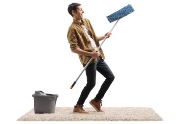 Mutlu adam dans ediyor ve beyaz arka planda izole edilmiş temizlik paspası ile hava gitarı yapıyor.