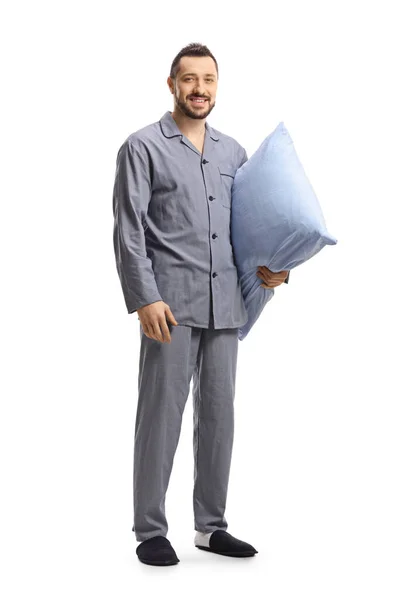 一个穿着睡衣的年轻人拿着枕头 对着被白色背景隔开的相机微笑的全长肖像 — 图库照片
