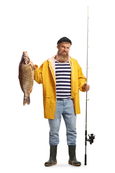 一个渔夫拿着一根钓竿和一条被白色背景隔离的鲤鱼的全长肖像 — 图库照片