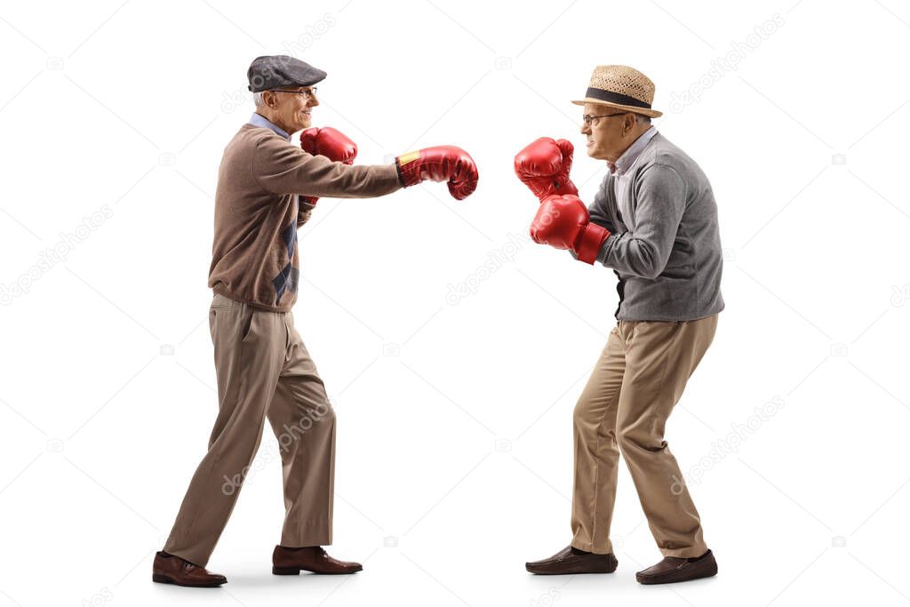 Full length profile shot of two elderly man fighting with boxing gloves isolated on white background