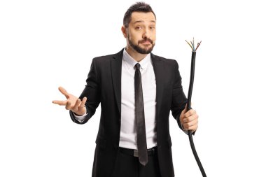 Kafası karışmış bir iş adamı kırık bir elektrik kablosu tutuyor ve beyaz arka planda izole edilmiş kameraya bakıyor.