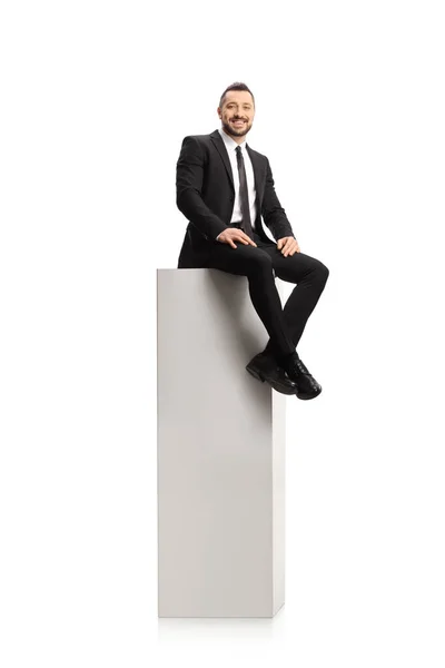 Takım Elbiseli Kravatlı Bir Adam Uzun Beyaz Bir Sütunda Oturuyor — Stok fotoğraf