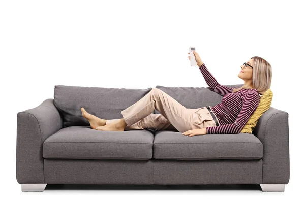Young Woman Gray Sofa Holding Remote Control Unit Isolated White — Stock Photo, Image