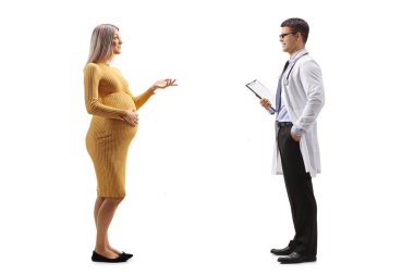 Sarı elbiseli hamile bir kadının beyaz arka planda izole edilmiş bir doktorla konuşurken tam boy profil fotoğrafı.