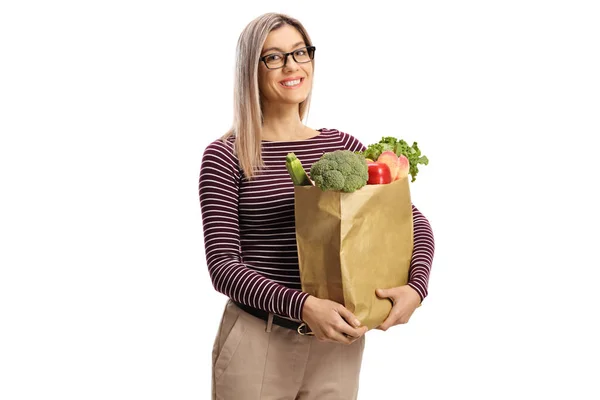 带着眼镜的金发女人提着一个纸袋 纸袋上有白色背景的杂货 — 图库照片