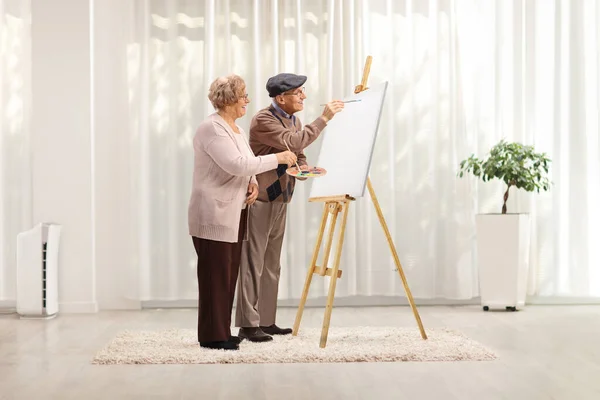 リビングルームで自宅でキャンバス上のブラシで高齢者のカップル絵画 — ストック写真