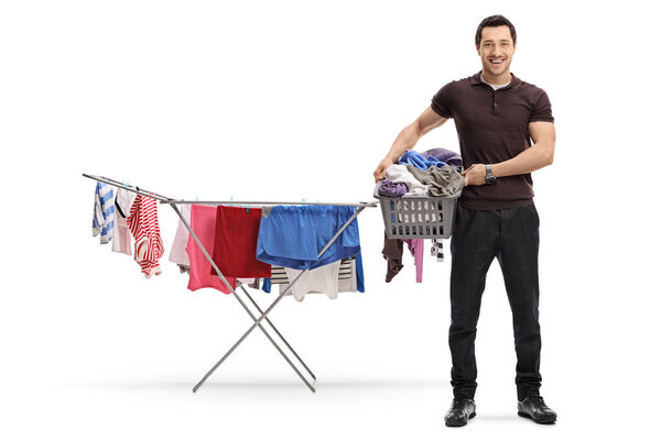 Full length portrait of a young man with a laundry basket and a line drying clothes rack isolated on white background