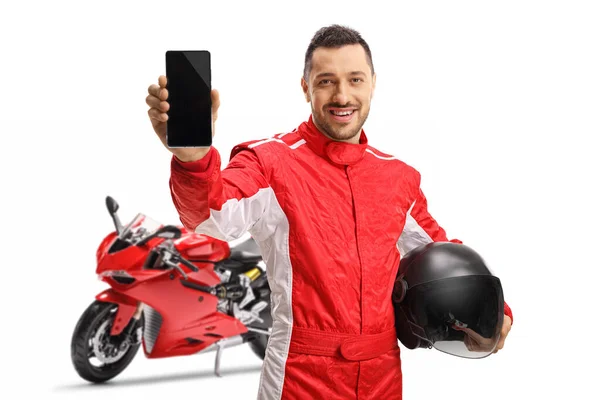 携帯電話を示すジャンプスーツのオートバイレーサーと白い背景に隔離されたヘルメットを保持 — ストック写真
