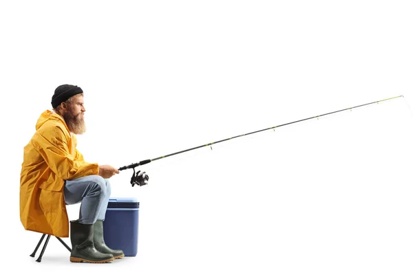 一个留着胡子的渔夫拿着一根钓竿在白色背景的椅子上捕猎的照片 — 图库照片