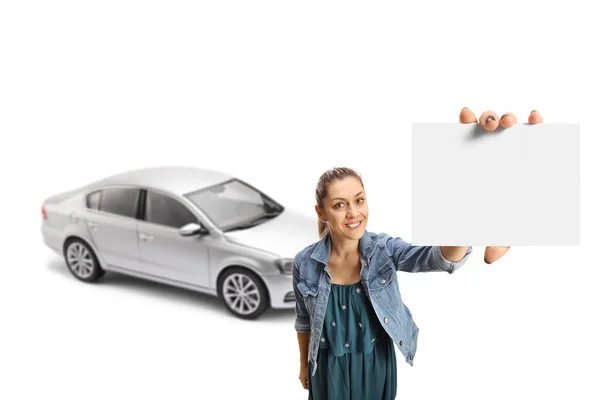 白い背景に隔離されたカメラの前に空白のカードを示す銀の車を持つカジュアルな若い女性 — ストック写真