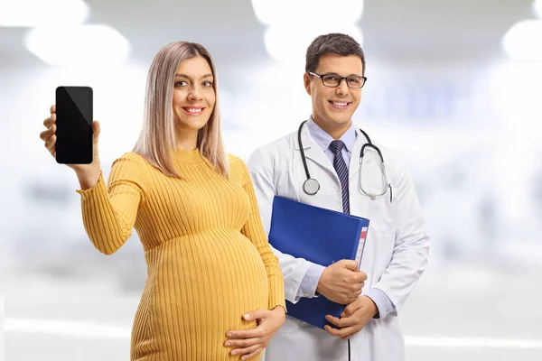 男医生和一个拿着手机笑着的孕妇 — 图库照片