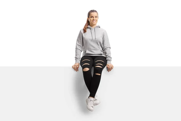 Glimlachende Jonge Vrouw Een Hoodie Gescheurde Broek Zitten Een Paneel — Stockfoto