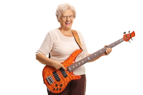 拿着电贝司吉他的老年妇女对着被白色背景隔离的摄像机笑着 — 图库照片