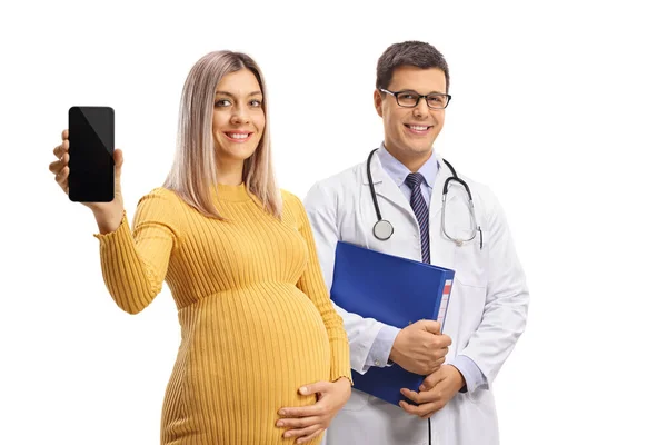 妊娠中の女性は携帯電話を持っていて 白い背景に孤立したフォルダを持つ男性医師の隣に立っている — ストック写真
