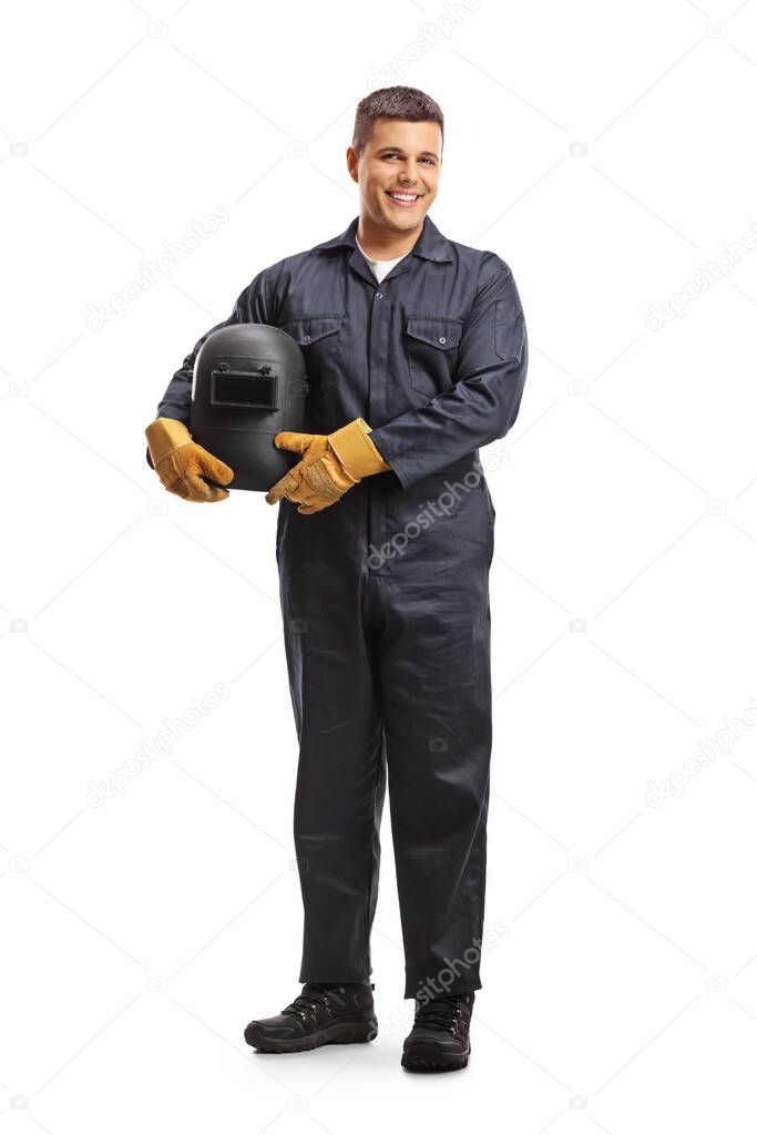 Full length portrait of a welder in a uniform holding a protective helmet and smiling at camera isolated on white background