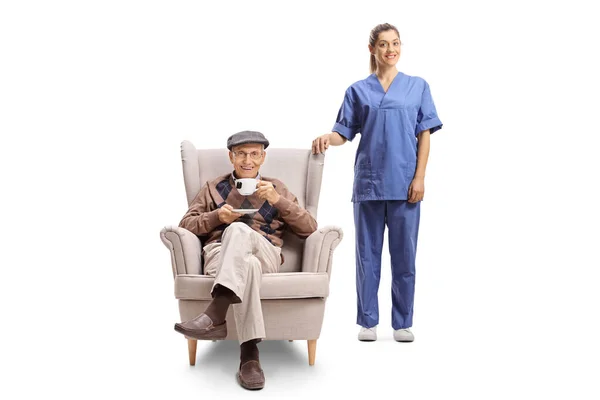 Female Nurse Posing Elderly Man Armchair Cup Tea Isolated White — Stock Photo, Image