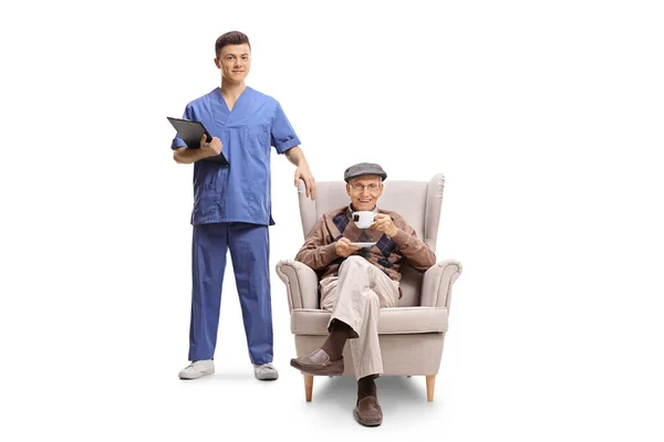 Young Male Health Worker Clipboard Standing Next Elderly Man Armchair — Stock Photo, Image