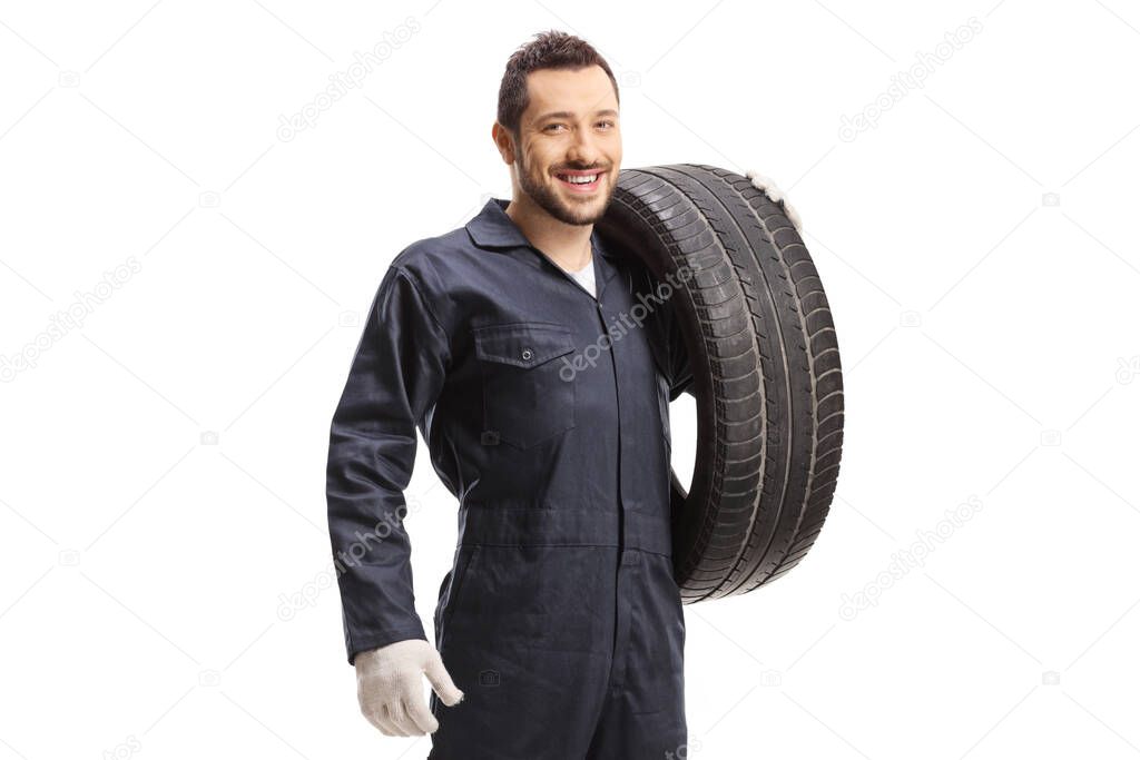Mechanic holding a car tire and smiling at the camera isolated on white background