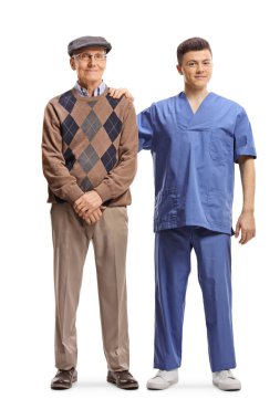 Beyaz arka planda izole edilmiş yaşlı bir adamın yanında duran genç bir erkek fizyoterapistin tam boy portresi