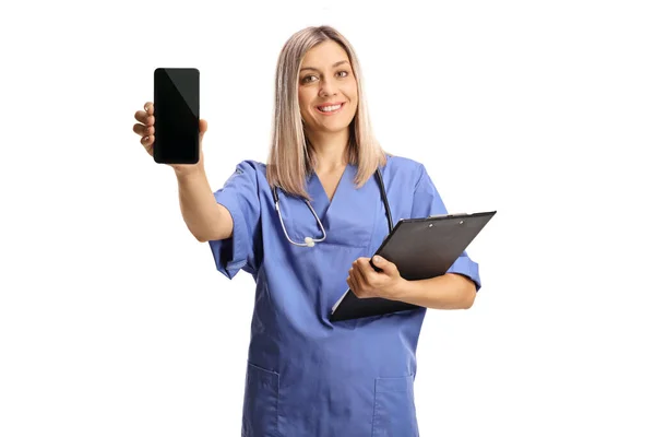 Enfermera Uniforme Azul Sosteniendo Portapapeles Mostrando Teléfono Móvil Aislado Sobre — Foto de Stock