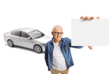 Yeni arabası olan mutlu, olgun bir adam elinde beyaz arka planda izole edilmiş boş bir kart tutuyor.