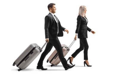 Beyaz arka planda yürüyen ve bavulları çeken genç bir işadamı ve iş kadınının tam boy profil çekimi.