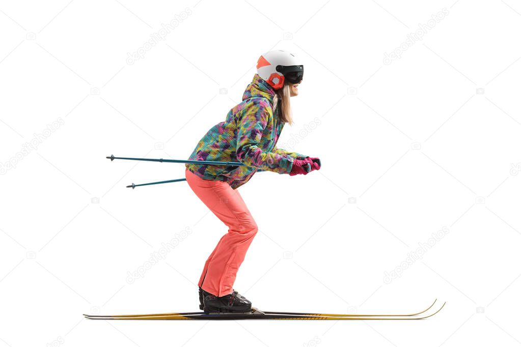 Full length profile shot of a female with a helmet skiing isolated on a white background