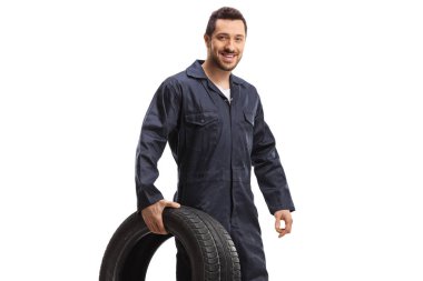 Otomobil tamircisi gülümsüyor ve beyaz arkaplanda izole edilmiş bir lastik tutuyor