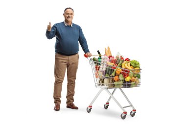 Elinde alışveriş arabası olan, beyaz arka planda izole edilmiş baş parmak işareti olan olgun bir adamın tam boy portresi.