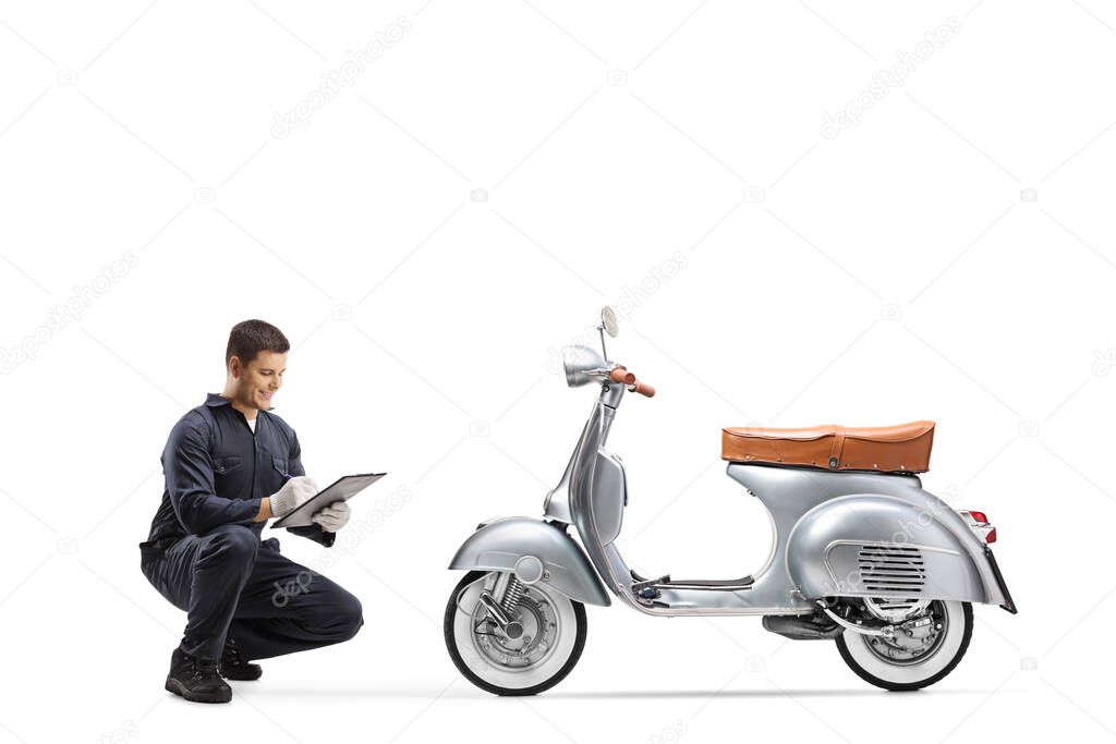 Motorbike mechanic kneeling and checking a vintage model scooter isolated on white background