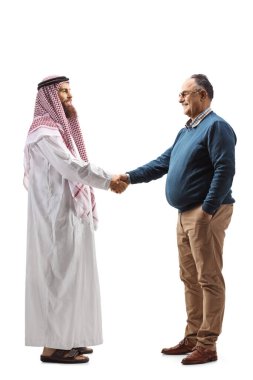 Beyaz arka planda soyutlanmış olgun bir adamla tokalaşan genç bir Suudi adamın tam boy profil çekimi.