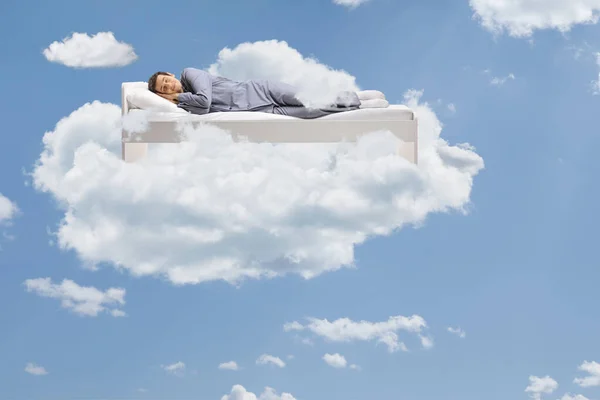 Man sleeping peacefully up in the clouds floating on his bed