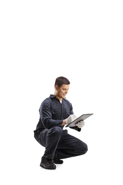 Technicus Een Uniform Knielen Schrijven Van Een Een Klembord Geïsoleerd — Stockfoto