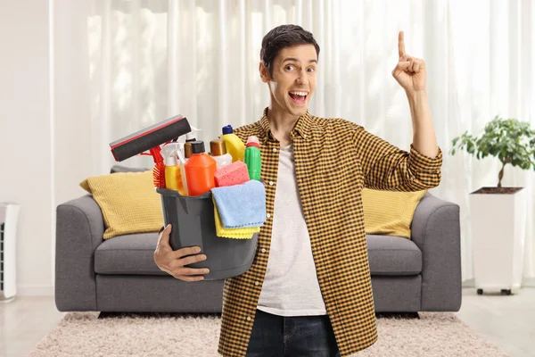 Joven Con Cubo Lleno Artículos Limpieza Una Sala Estar Apuntando — Foto de Stock