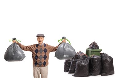 Beyaz arka planda izole edilmiş çöp kutusunun önünde çöp torbası olan yaşlı bir adam.