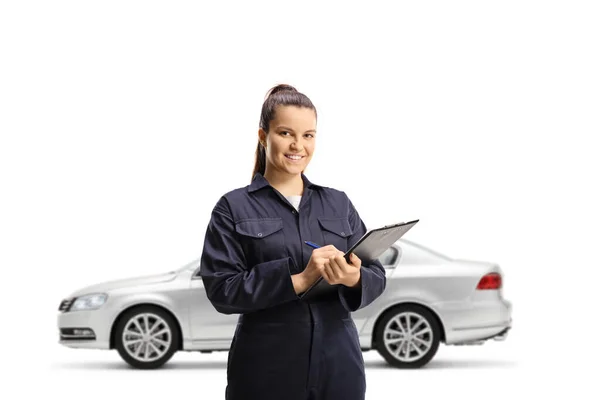 ドキュメントと白の背景に隔離されたクリップボードを保持銀車の前に女性の自動車整備士 — ストック写真