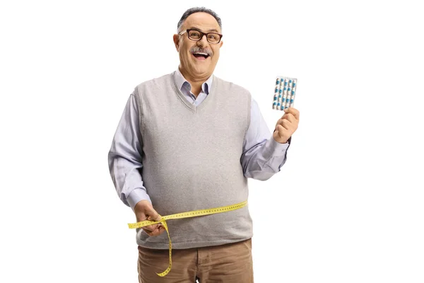 Šťastný Dospělý Muž Drží Hubnutí Pilulky Měření Jeho Pas Izolované — Stock fotografie