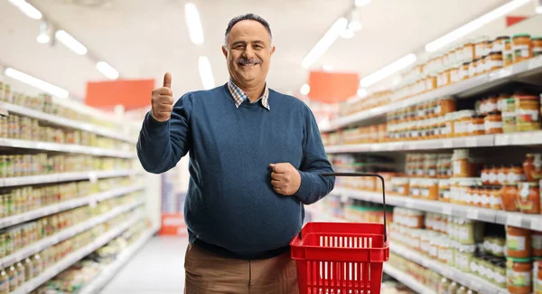 Mature Male Customer Holding Shopping Basket Supermarket Gesturing Thumb Sign — Stock Photo, Image