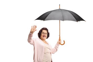 Beyaz arka planda şemsiye tutan ve el sallayan yaşlı bir kadın.